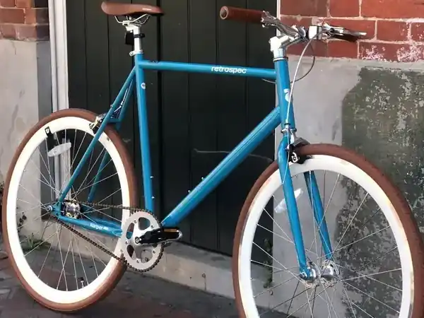 Blue Retrospec Road Bike with tan-sidewall tires displayed outside the Bike Rental New Orleans shop on Burgundy Street